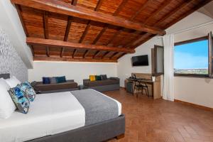 sypialnia z łóżkiem, kanapą i telewizorem w obiekcie Feudogrande Bio Relais Hotel w mieście Fiumefreddo di Sicilia