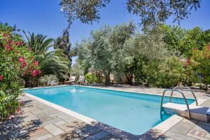 a swimming pool in a yard with trees and bushes at Charming Pink Villa in Skopelos Town