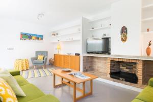 ein Wohnzimmer mit Kamin und Fernseher in der Unterkunft Can Roig -Caldes- in Colònia de Sant Pere
