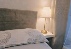 a bed with a pillow and a lamp on a night stand at zentrale Design-Ferienwohnung mit Balkon und Stellplatz in Karlsruhe - APOLONIAliving in Karlsruhe
