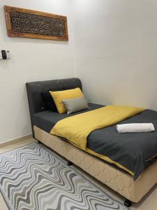 a bed with yellow and black sheets and a rug at COZY Residence Homestay Teluk Senangin Lumut in Lumut