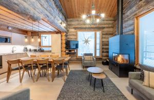 a living room with a dining room table and a fireplace at Aurinkorinne in Ruka