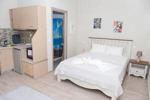 a bedroom with a large white bed and a kitchen at Ύδνα studios in Pefki