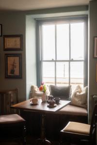 a living room with a table and a large window at The Old Success Inn in Sennen Cove