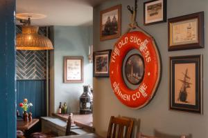 a plate hanging on a wall with pictures on it at The Old Success Inn in Sennen Cove