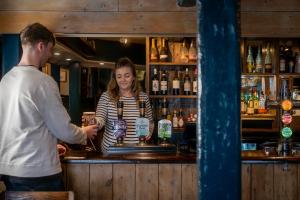 a man and a woman standing at a bar at The Old Success Inn in Sennen Cove