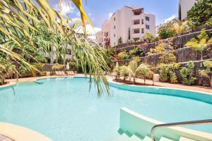 a swimming pool with a palm tree and buildings at Colinas - Timanfaya 03 VISTA RESERVA NATURAL Y JARDIN in Palm-mar