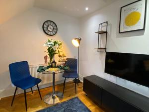 a living room with a table and chairs and a clock at Pinnacle Apartment in Reading
