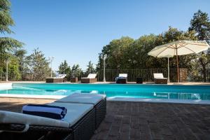 una piscina con lettini e un ombrellone di Villa Piscina La Trinità a Corciano