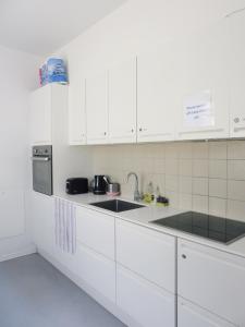 a white kitchen with white cabinets and a sink at close to norreport st & central 302 - norregade 34a 3 kobenhavn 1165 in Århus Østbanegård