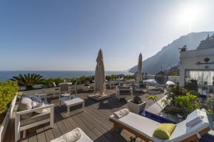 patio z leżakami i parasolami oraz oceanem w obiekcie Villa Pietra Santa w mieście Positano