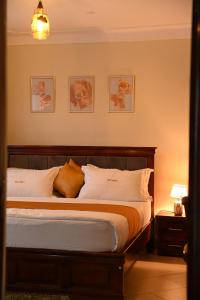 a bedroom with a large bed with white pillows at Hotel Casabella in Entebbe +5 photos