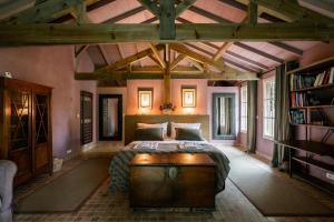 a bedroom with a large bed with a wooden table at Villa La Maison Rose in Saint-Julien-en-Born