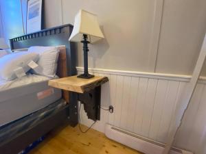a lamp on a table next to a bed at Trinity's Oceanview Gem St Paul's Schoolhouse in Trinity