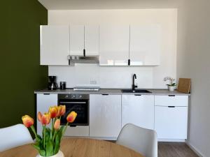 a kitchen with white cabinets and a table with tulips at Apartmenthaus Walram in Bocholt