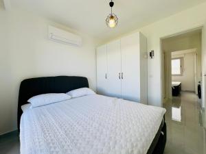 a bedroom with a white bed with a black headboard at Çilek Suit Dalyan in Cesme