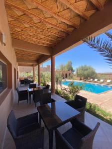 a patio with tables and chairs and a swimming pool at Auberge Famille Benmoro in Skoura