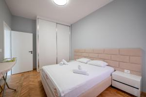 a bedroom with a large white bed and a table at Huna Apartment in Sarandë