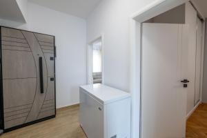 a white kitchen with a refrigerator and a door at Huna Apartment in Sarandë +37 photos