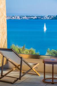 uma cadeira e um banco em frente a uma vista para o oceano em Hotel Ola - Adults Only em Trogir