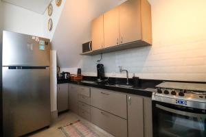 a kitchen with white cabinets and a stainless steel refrigerator at Servico de Praia em Juquehy com Piscina Aquecida in Juquei
