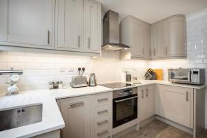 a white kitchen with white cabinets and appliances at Eagles Nest - By Rowes Retreats in Falmouth
