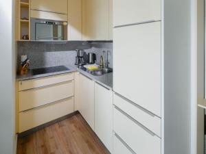 une cuisine avec des armoires blanches et des appareils en acier inoxydable dans l'établissement Appartement Sonnengelb, à Norderney 6 autres photos