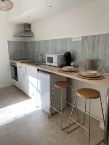 a kitchen with a counter with stools and a microwave at Auma Home in Bordeaux
