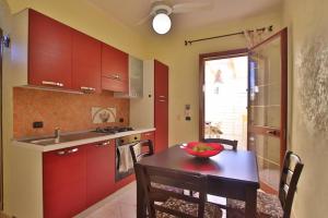 a kitchen with red cabinets and a table with a bowl of fruit on it at Casa Angela Lampedusa in Lampedusa