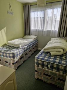 two twin beds in a room with a window at Parkview Retreat in Hemsby