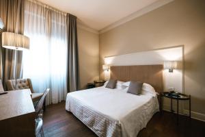 a hotel room with a white bed and a window at Hotel De La Ville in Riccione