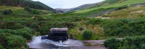a jeep driving down a dirt road on a hill at Land Rover Defender Camper Hire in Morpeth