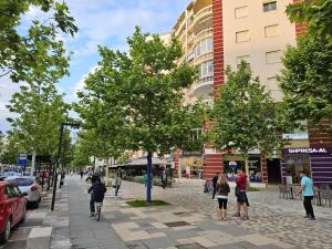 ヴロラにあるGEARD Apartamentの木々や建物が並ぶ道を歩く人々