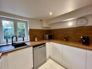 a kitchen with white cabinets and a clock on the wall at Beau T3 à 15 min de Lyon in Pierre-Bénite +23 photos