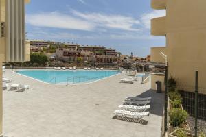 a swimming pool with lounge chairs and a resort at Tu Alojamiento En Playa Paraiso in Adeje