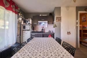 a kitchen with a long table with chairs in it at Charmant studio en montagne à Allevard - 30 m² avec balcon in Allevard
