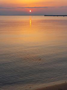 a sunset over a body of water with the sun setting at Philoxenia Beach Apartments Stavros in Stavros