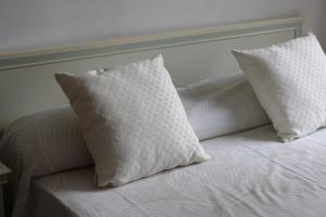 2 almohadas blancas sentadas en una cama blanca en Relax e Comfort Maiori Family Apt 250m to Beach, en Maiori