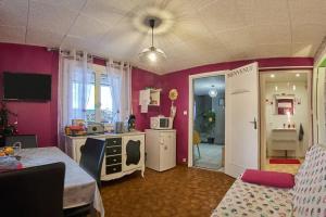 a kitchen with pink walls and a table and a kitchen with a microwave at Appartement charmant à Saint-Victor-de-Cessieu - 30 m² - Terrasse in Saint-Victor-de-Cessieu +7 photos
