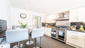 Una cocina con gabinetes blancos y un horno de estufa. en Burgess Beach House, en Caister-on-Sea