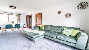Una sala de estar con un sofá verde y una mesa. en Burgess Beach House, en Caister-on-Sea