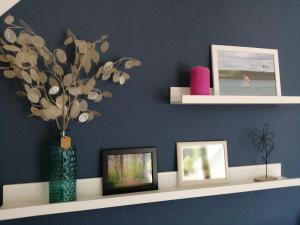 a shelf with pictures and a vase with flowers in it at Ferienwohnungen am Waldbad Zwenkau in Zwenkau