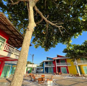 a group of buildings with tables and a tree at Pousada Vila ÁguaMar in Itapoa +10 photos