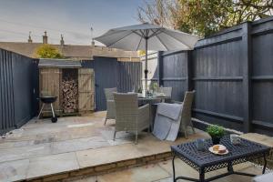 un patio con una mesa y una sombrilla en Little Gem Cottage Luxury cottage Bourton, dog friendly, parking, Gdn, en Bourton on the Water