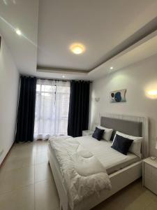 a bedroom with a large bed and a window at Aramis Apparments in Nairobi