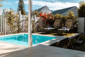 a swimming pool with chairs next to a white fence at The Crescent Hideaway in Franschhoek