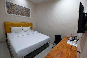 a small room with a bed and a flat screen tv at Grand Mulia Hotel Kisaran in Kisaran