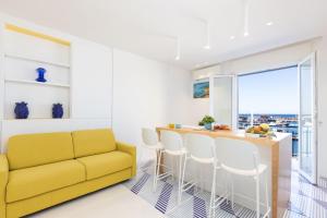 a kitchen with a yellow couch and a counter with stools at Estate4home - Mary B in Piano di Sorrento