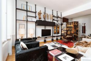 a living room with black furniture and a tv at Youhosty - Brera 17 in Milan