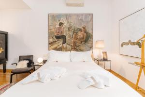 a bedroom with a white bed with a painting on the wall at Youhosty - Brera 17 in Milan